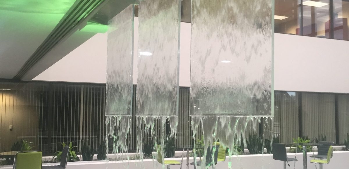 Green lit water feature outside of building